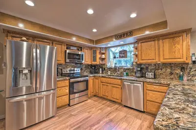 a kitchen with wooden cabinets and stainless steel appliances at Near Hiking Trails Cabin with Deck in Pioneer! in Pioneer