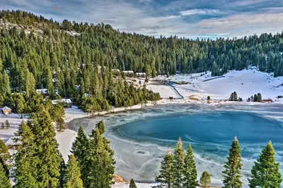 a blue lake in the middle of a snow covered forest at Pinecrest Retreat with Fireplace! in Pinecrest