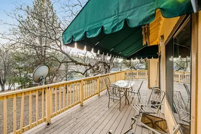 a deck with a table and chairs and a green umbrella at Luring Lakefront Landing in Groveland