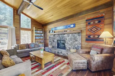 a living room with a stone fireplace in a cabin at Indian Hill Hush in Truckee