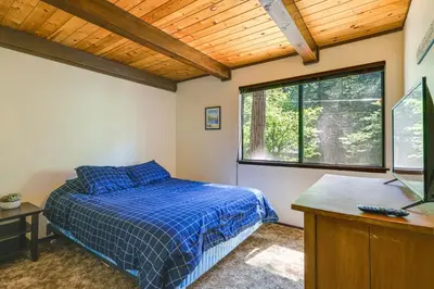 a bedroom with a bed and a desk and a window at Cabin with Deck and Fire Pit in Blue Lake Springs! in Arnold