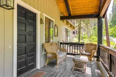 a porch with wicker chairs and a black door at Cabin with Deck and Fire Pit in Blue Lake Springs! in Arnold