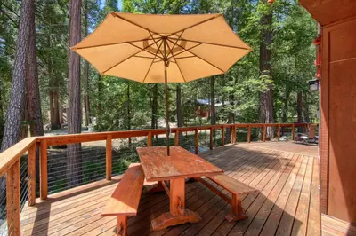 a wooden bench with an umbrella on a deck at 92R Jolie Cabin in North Wawona