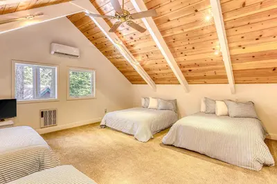 two beds in a room with wooden ceilings at Flicker Retreat in Homewood