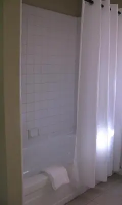 a bathroom with a tub and a white shower curtain at 5th Street Inn in Mariposa