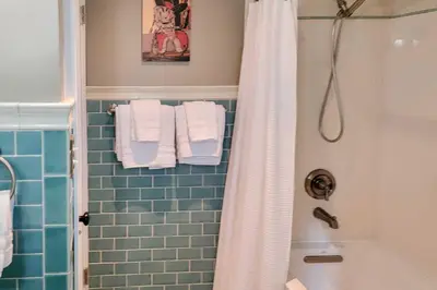 a bathroom with a shower and a blue tiled wall at Ski, Shop and Explore Walkable Midtown Reno Oasis! in Reno