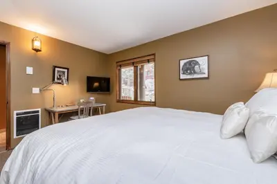 a bedroom with a large white bed and a desk at Helios 11N in Mammoth Lakes