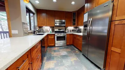 a kitchen with wooden cabinets and a stainless steel refrigerator at Mammoth Estates 2 Bedroom Condos Near Mammoth Village in Mammoth Lakes