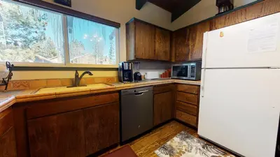 a kitchen with wooden cabinets and a white refrigerator at 2 Bedroom Condos at Mammoth Estates - Near Mammoth Village! in Mammoth Lakes