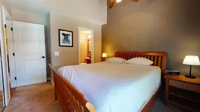 a bedroom with a large bed with white sheets at Mammoth Estates Deluxe 2 Bedroom Condos in Mammoth Lakes
