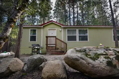 a green tiny house in the woods with rocks at 3R Suter's Forte in North Wawona