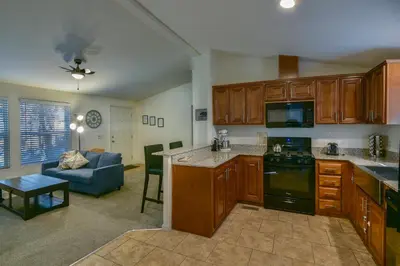 a kitchen with wooden cabinets and a living room at 3R Suter's Forte in North Wawona