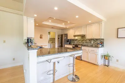 a large kitchen with white cabinets and granite counter tops at Spectacular Views w/ Hot Tub/BBQ -Yosemite & Bass Lake in Oakhurst