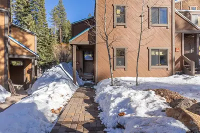 a house with snow on the ground next to a building at Cozy Aspen Grove 2 bed 2 bath condo in Truckee
