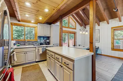 a kitchen with white cabinets and a wooden ceiling at Seclusion in Style in Truckee