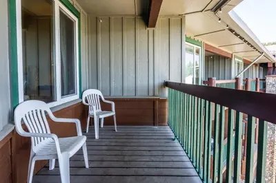 two white chairs sitting on the porch of a house at Juniper Springs Lodge #413 - Luxury Ski in Ski out! 2 Bedroom in Mammoth Lakes