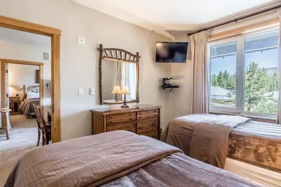 a bedroom with two beds and a mirror and a window at Juniper Springs Lodge #413 - Luxury Ski in Ski out! 2 Bedroom in Mammoth Lakes