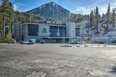a large building with cars parked in front of a mountain at Contemporary Mountain Retreat - Walk to Slopes! in Mammoth Lakes