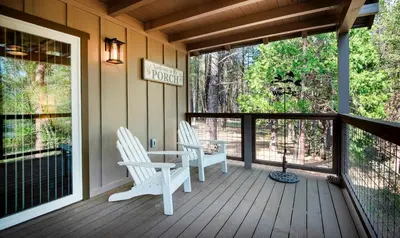 a porch with two white chairs and a table on it at 12R Hilltop Haven in North Wawona
