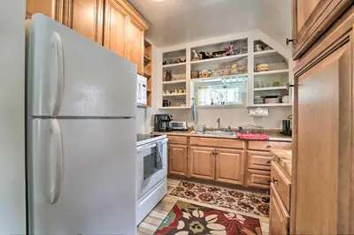 a kitchen with a white refrigerator and wooden cabinets at Half-Mi to Trails Rustic Soda Springs Cabin! in Soda Springs