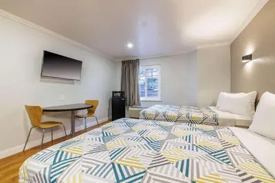a hotel room with two beds and a table at Motel 6-Auburn, CA in Auburn