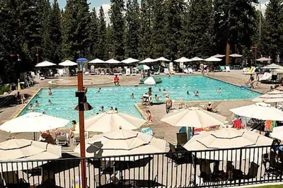 a large swimming pool with people in it with umbrellas at DNA Chalet - Newly Renovated Townhome @ Northstar in Truckee