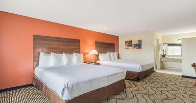 two beds in a hotel room with orange walls at Best Western Roseville Inn in Roseville