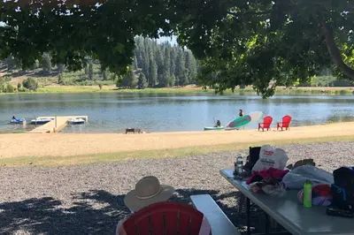 a picnic table with people on the shore of a lake at High Sierra Retreat with a view of Pinecrest lake in Pinecrest