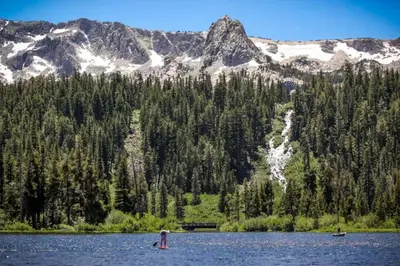 two people in a lake with mountains in the background at La Residence 8 in Mammoth Lakes