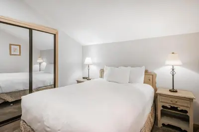 a bedroom with a large white bed and a mirror at Through the Trees in Truckee