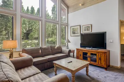 a living room with couches and a flat screen tv at Through the Trees in Truckee