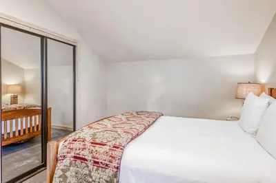 a bedroom with a white bed and a window at Through the Trees in Truckee
