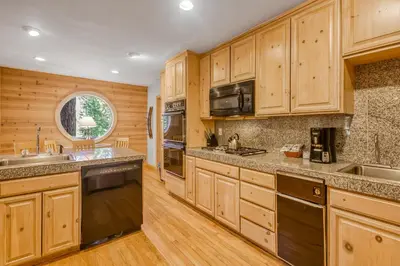 a large kitchen with wooden cabinets and a window at Through the Trees in Truckee