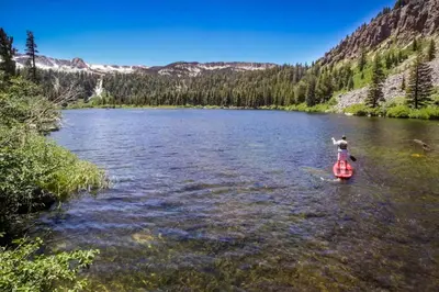 a person is standing on a kayak in a river at La Residence N3 in Mammoth Lakes