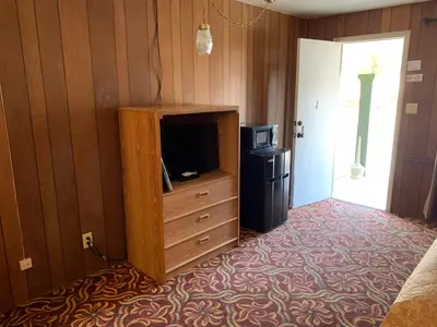 a room with a tv and a dresser with a tvictericter at El Portal Motel in Beatty