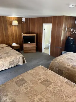 a hotel room with two beds and a flat screen tv at El Portal Motel in Beatty