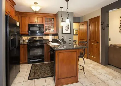 a kitchen with wooden cabinets and a black refrigerator at St Anton Courtyard View Ski-In and Out 1 Bedroom Condo in Mammoth Lakes