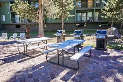 a group of picnic tables and benches in front of a building at St Anton Condos with Rec Center in Mammoth Lakes