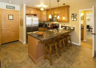 a kitchen with a refrigerator and some bar stools at St Anton Street View 2-Bedroom Condo with full kitchen in Mammoth Lakes