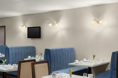 a dining room with tables and blue chairs and a tv at National Hotel Jackson, Tapestry Collection by Hilton in Jackson