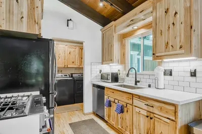 a kitchen with wooden cabinets and a black refrigerator at The Lazy Golden Cabin in South Lake Tahoe