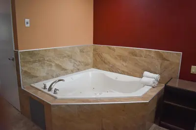 a bath tub in a bathroom with brown tile at Baymont by Wyndham Manteca in Manteca