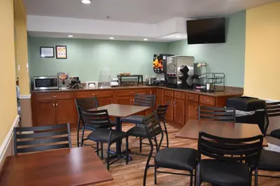 a restaurant with wooden tables and chairs and a kitchen at Baymont by Wyndham Manteca in Manteca