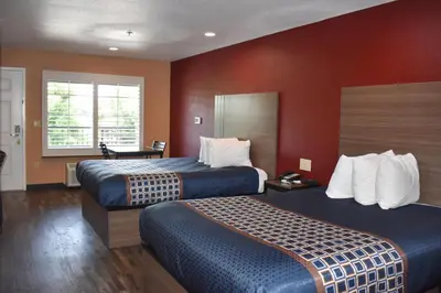 a hotel room with two beds and red walls at Baymont by Wyndham Manteca in Manteca