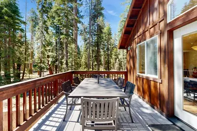 a wooden deck with a table and chairs on it at Sugar Pine Haus in Tahoma