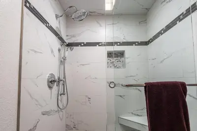a bathroom with a shower with white marble walls at Brand New Listing! 5 minute walk to Canyon Lodge! Newly Updated Two-Bed, Two-Bath, Mountainback #14 in Mammoth Lakes