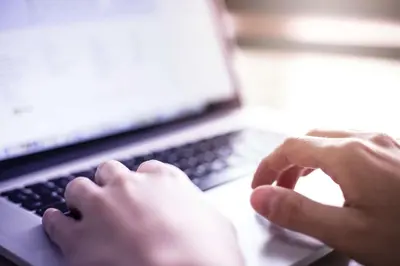 a person is typing on a laptop computer at La Quinta by Wyndham Los Banos in Los Banos