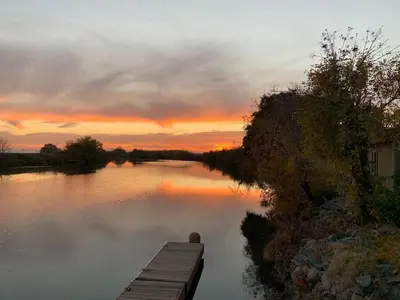 a sunset over a lake with a wooden dock at Year-round fishing, boating, birding, 1 hr from SF in Walnut Grove