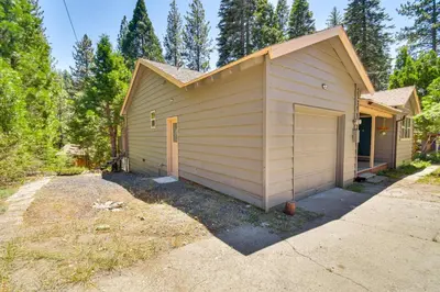 a small house with a garage next to a driveway at Cozy Retreat with Deck about 2 Mi to Pinecrest Lake! in Strawberry