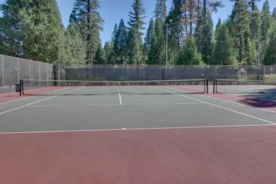 a tennis court with a net and trees at Worth The Waite in Arnold